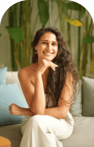 Amira Attar smiling, seated among green plants