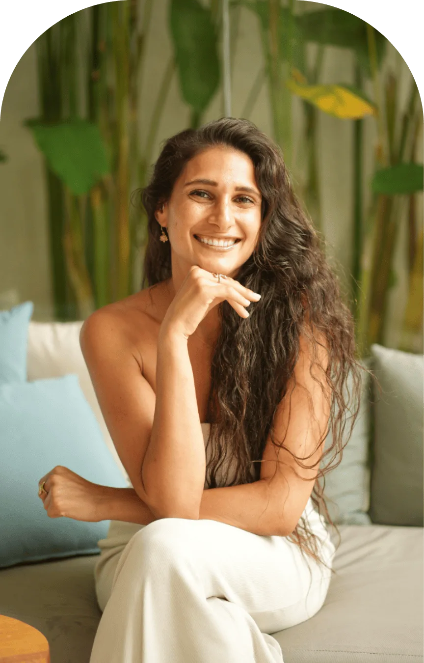 Amira Attar smiling, seated among green plants