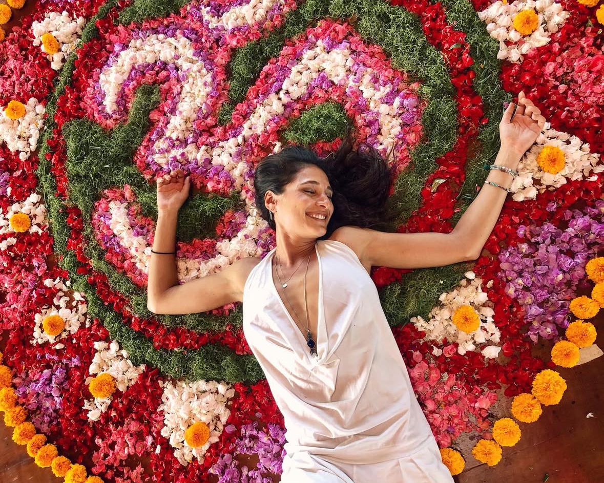 Amira Attar lying in a flower mandala